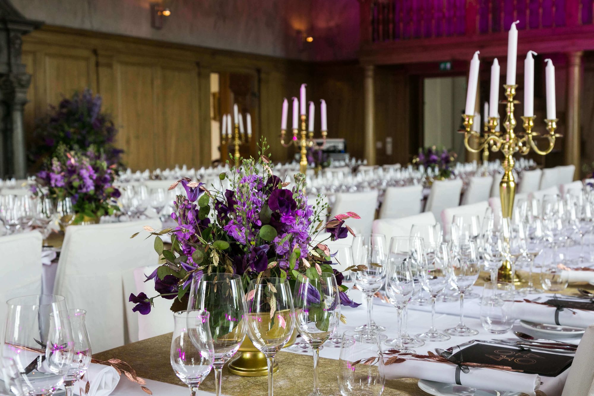 Två fint uppdukade långbord med lika blomster och stora ljusstakar på Ulfsunda Slott