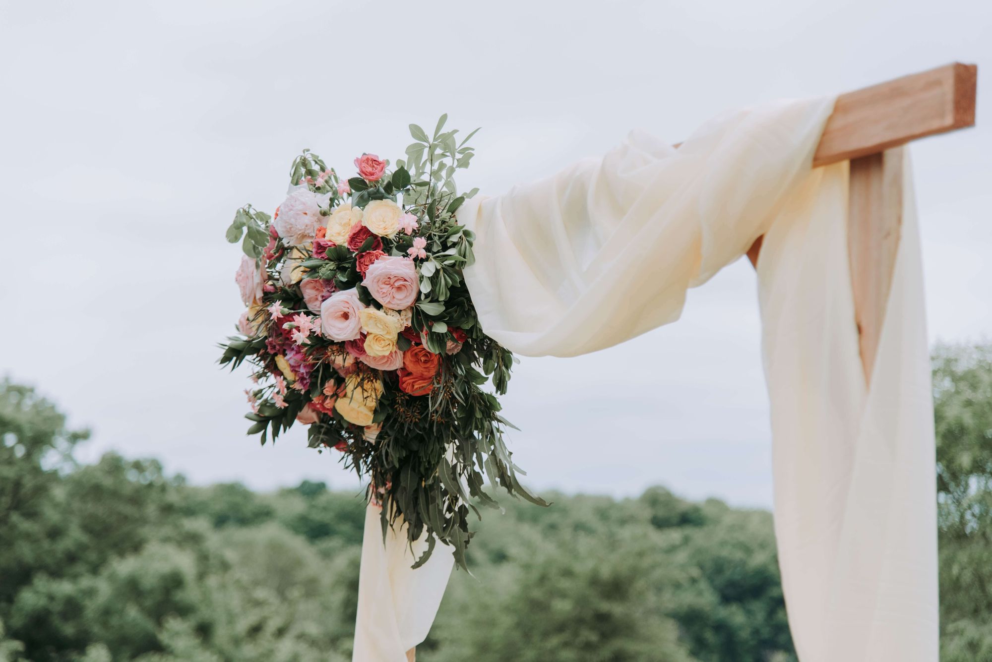 Bröllopsbåge med färska blommor och vitt tyg