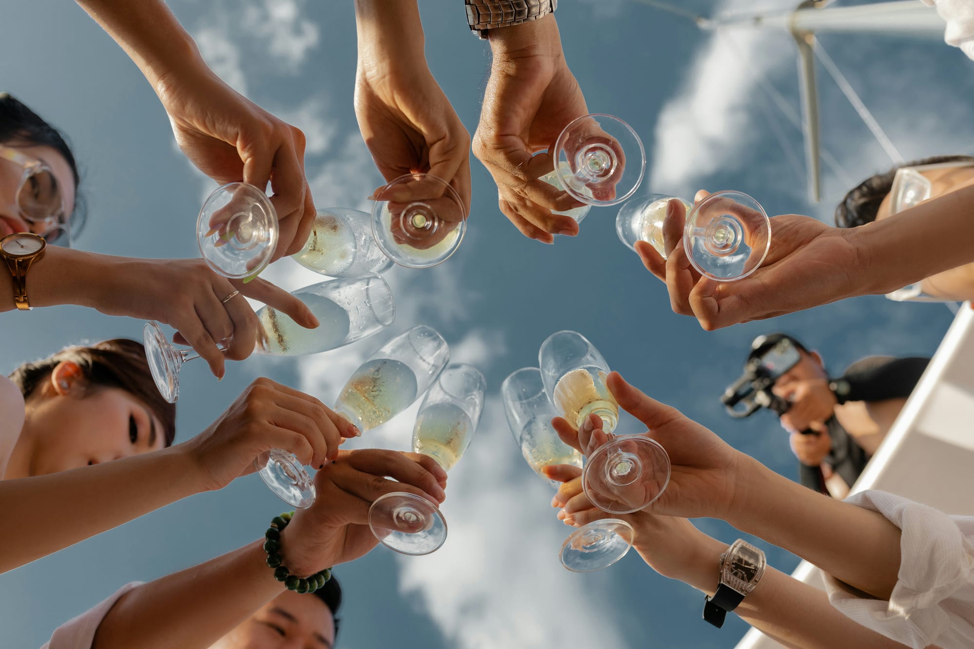 Grupp av vänner som skålar med champagneglas mot en blå himmel. En stämningsfull möhippa fylld med lekar, skratt och firande!