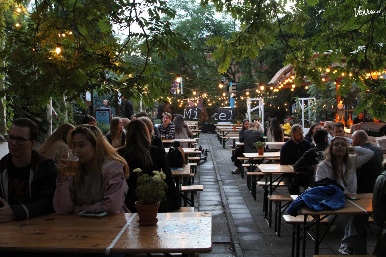 Bild av den grönskande trädgården vid Moriska Paviljongen i Malmö, en idealisk plats för en utomhus sommarfest.