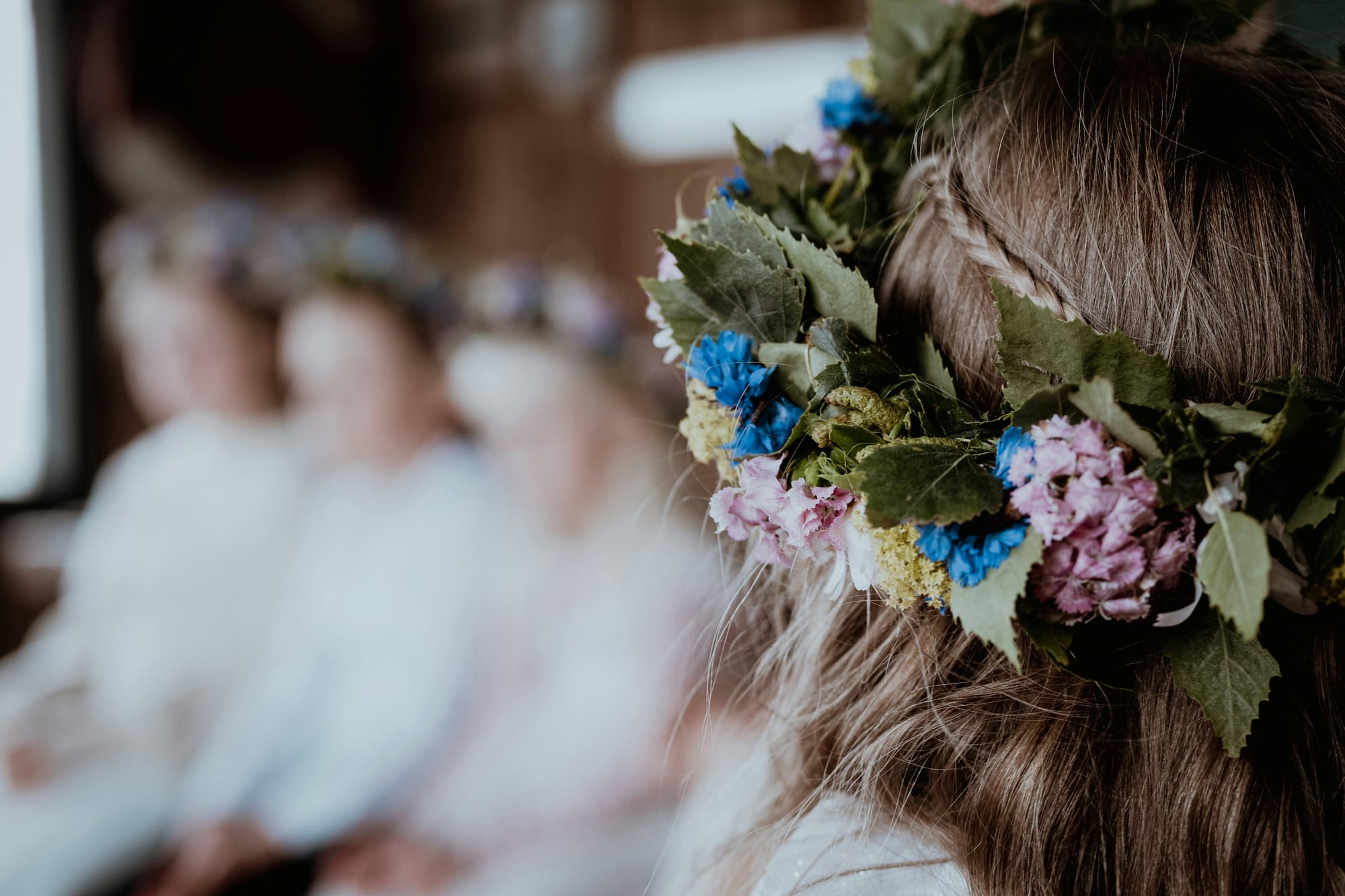 Barn med midsommarkrans i håret under midsommarfirande, med fokus på de färgglada blommorna.