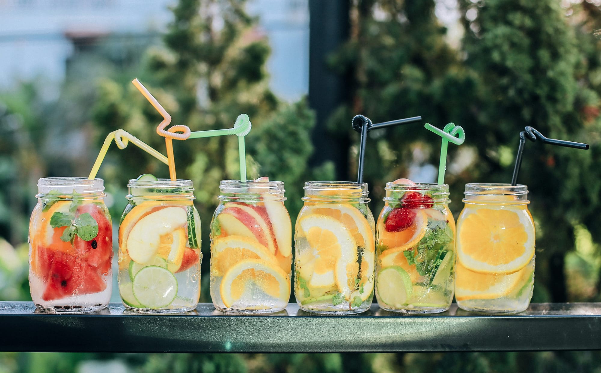 Somriga fruktdrinkar i glasburkar redo för gästerna – en snygg och läskande sommarfest dekoration och aktivitet vid drinkbordet.