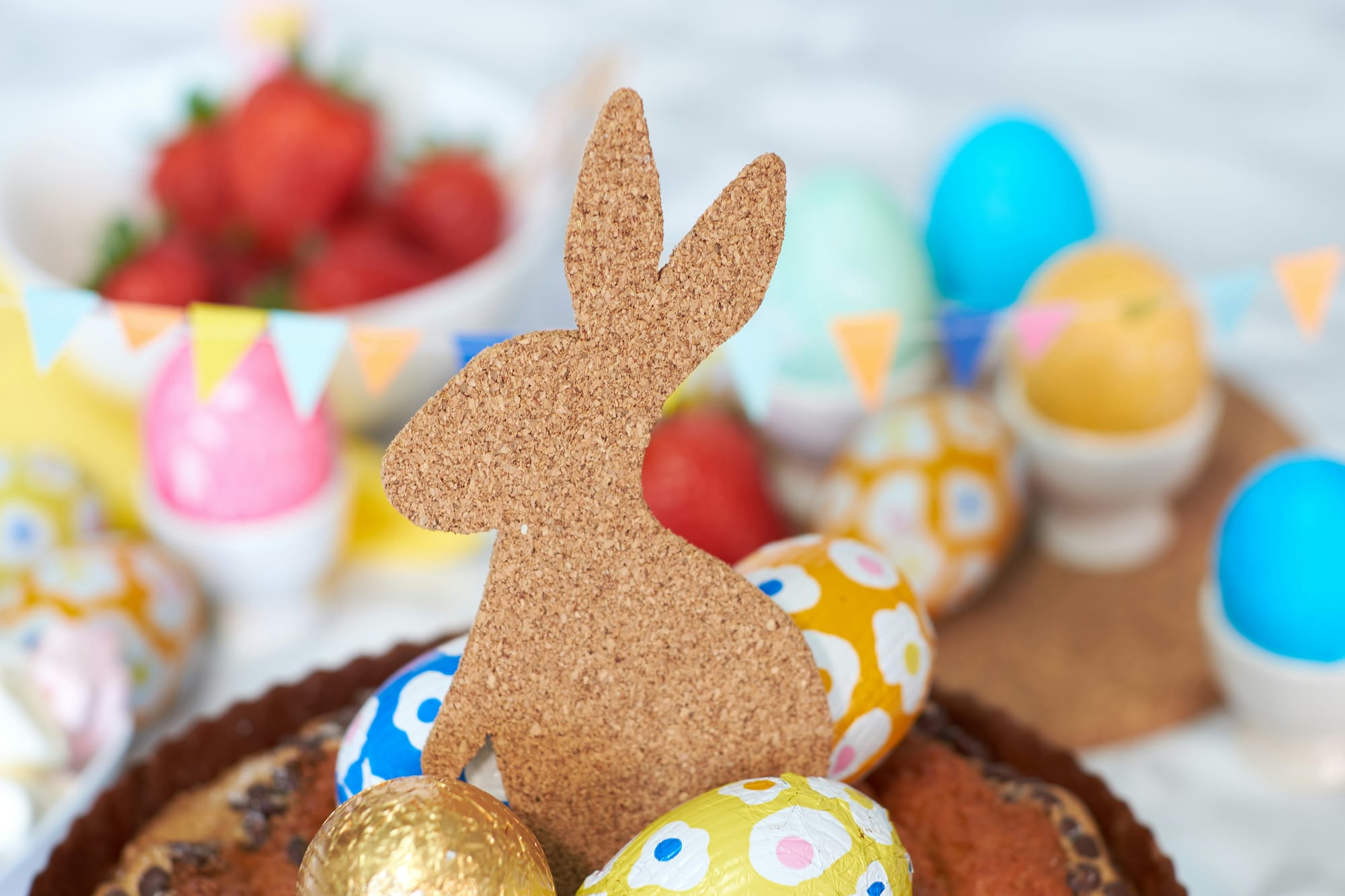Påskbord dekorerat med chokladägg, korkkanin och färgglada detaljer – inspiration till en inbjudande och vårig påskfest.